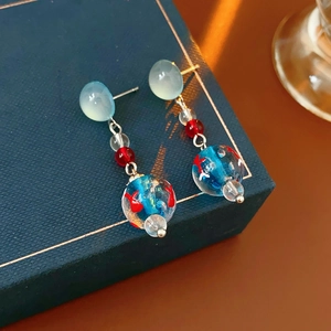 Detailed close-up of starfish style drop earrings with blue glass beads on luxury packaging