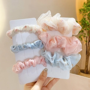 Detailed close-up of colorful floral print chiffon hair scrunchies on white cards