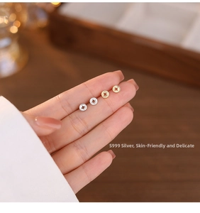 Close-up of S999 sterling silver and gold coin stud earrings held by hand