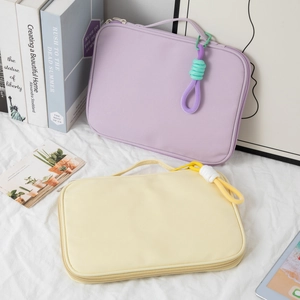 Detail of minimalist laptop sleeve with colorful braided zipper pull on white fabric