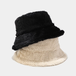 Détail de bobs en peluche noir et beige montrant la texture épaisse en fausse fourrure
