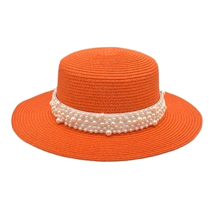 Détail du chapeau de soleil orange en paille tressée avec bandeau de perles