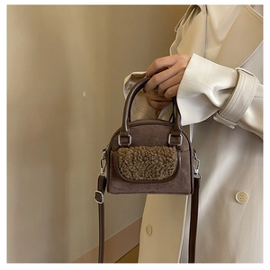 Close-up of brown suede handbag with plush khaki trim and adjustable leather strap