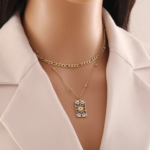 Close-up of double-layer gold necklace featuring a Cuban chain and evil eye enamel pendant