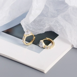 Macro shot of gold hoop earrings featuring a heart-shaped zircon and pave rhinestones