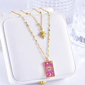 Detail of double-layer gold necklace with star pendant and purple tarot enamel plaque