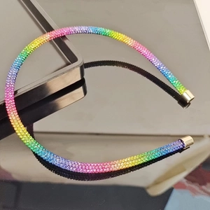 Detail of a thin rainbow rhinestone headband with gradient crystals and gold metal ends