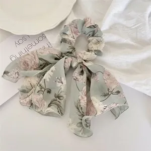 Détail d'un chouchou en mousseline fleurie avec ruban long sur une assiette décorative