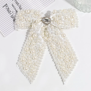 Close-up of white ribbon bow hair clip with faux pearls and sparkling rhinestone centerpiece