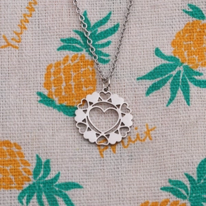 Detailed close-up of a silver hollow round pendant featuring heart patterns on a chain