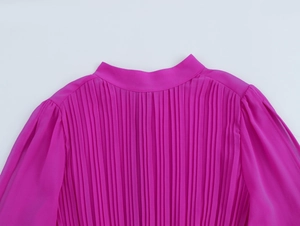 Dettaglio di un elegante abito in chiffon rosa plissettato con collo alto