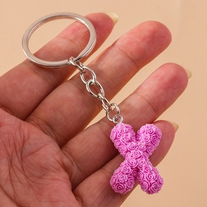 Detail of purple letter X keychain featuring delicate rose floral textures and silver chain