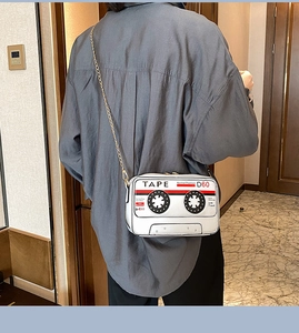 Detail of white cassette tape shoulder bag with gold chain strap on model's back
