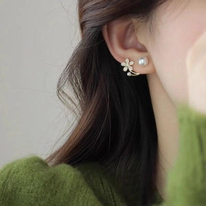 Detail shot of a model wearing elegant gold pearl flower earrings with micro-inlaid stones