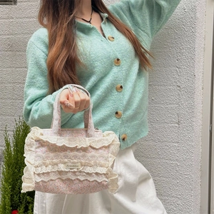 Détail du sac cabas en toile florale avec bordure en dentelle blanche et motifs de fleurs roses