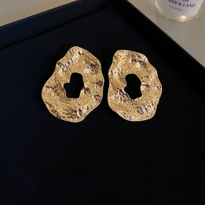 Detail of gold geometric earrings with hammered metal texture in a luxury gift box