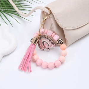 Pink silicone bead keychain wristlet with Mom charm and tassel on a beige bag