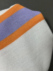 Dettaglio ravvicinato della trama a maglia con strisce arancioni e viola su bianco