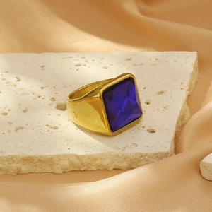 Detailed shot of a gold signet ring with a large blue zircon on white stone and silk