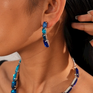 Detailed view of luxury silver-tone earrings and necklace with blue rectangular crystals