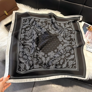 Gros plan d'un foulard carré en soie à motif cachemire noir et blanc sur tapis