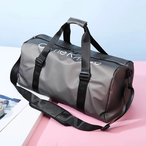 Détail du sac de fitness cylindrique gris avec sangles noires sur fond bleu et rose