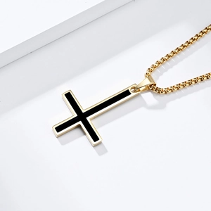 Detail of gold inverted cross pendant with black enamel inlay on beaded chain link