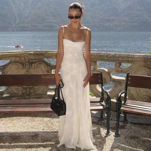 Outdoor shot of a white backless evening dress with embroidery and a flowing skirt