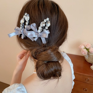 Détail de barrettes en satin gris avec strass portées sur une coiffure élégante relevée