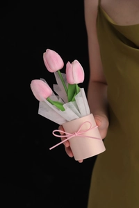 Close-up of three pink artificial PU tulips in a matching pink cylindrical vase with bow