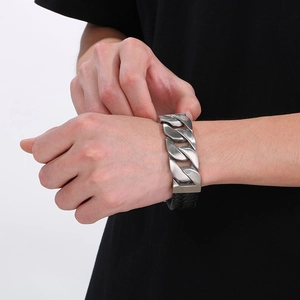 Close-up of men's black braided leather bracelet with silver cuban chain on wrist