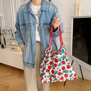 Detailed shot of canvas tote bag featuring red floral prints and thick cotton rope handles