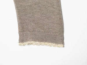 Close-up of light brown knitted sleeve cuff with elegant white lace trim detail