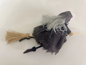 Detailed view of Halloween witch doll hanging with black burlap outfit and straw broomstick