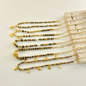 Detailed view of faceted tiger eye beads with gold charms and shell pendants on chains