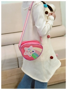 Sac bandoulière pailleté rose en forme de cœur avec sangle arc-en-ciel porté par un enfant