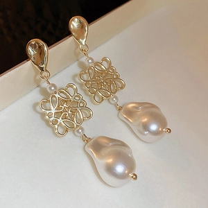 Elegant vintage gold earrings with baroque pearls and hollow knot design on silk background