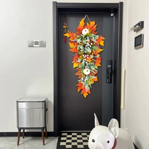 Detail of autumn teardrop wreath with pumpkins and maple leaves on a dark wooden door