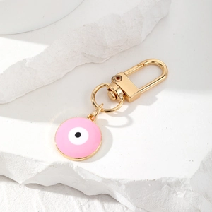Close-up of pink Evil Eye keychain with gold alloy lobster clasp on white stone