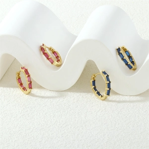 Detail showing gold hoop earrings with red and blue baguette-cut cubic zirconia stones