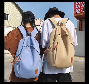 Outdoor shot of sky blue and beige nylon backpacks featuring a minimalist A letter print