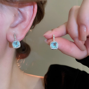 Close-up of square sea blue crystal drop earrings with halo gems on model