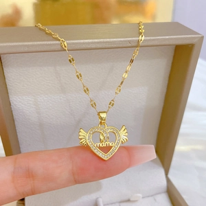 Detail of a golden heart necklace with wings and mama engraving shown in a jewelry box