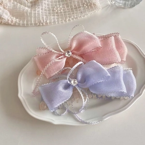 Gros plan de barrettes à griffes élégantes avec nœud en dentelle rose et violette