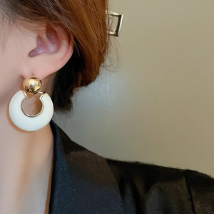 Minimalist French style gold and cream enamel hoop earrings worn by a model