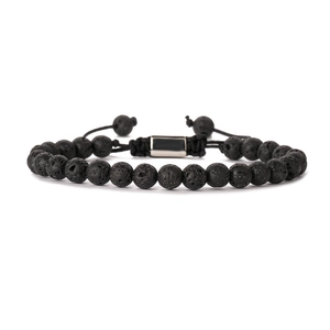 Detailed macro view of black volcanic lava stone beads and silver metal clasp on woven bracelet