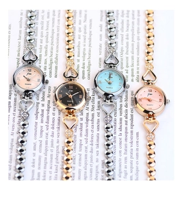 Flat lay of four elegant women's quartz watches with heart-shaped metal straps on book pages
