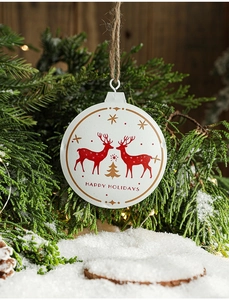Detail of round Christmas ornament with Happy Holidays text hanging on a tree branch