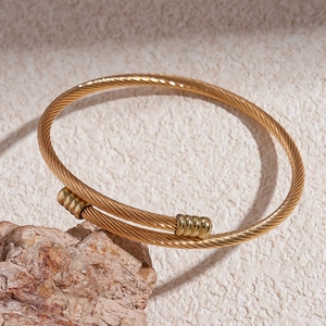 Macro detail of golden twisted cable bracelet with metallic cylindrical end caps