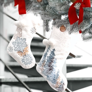 White plush Christmas stockings with snowflake and forest embroidery and pompom balls